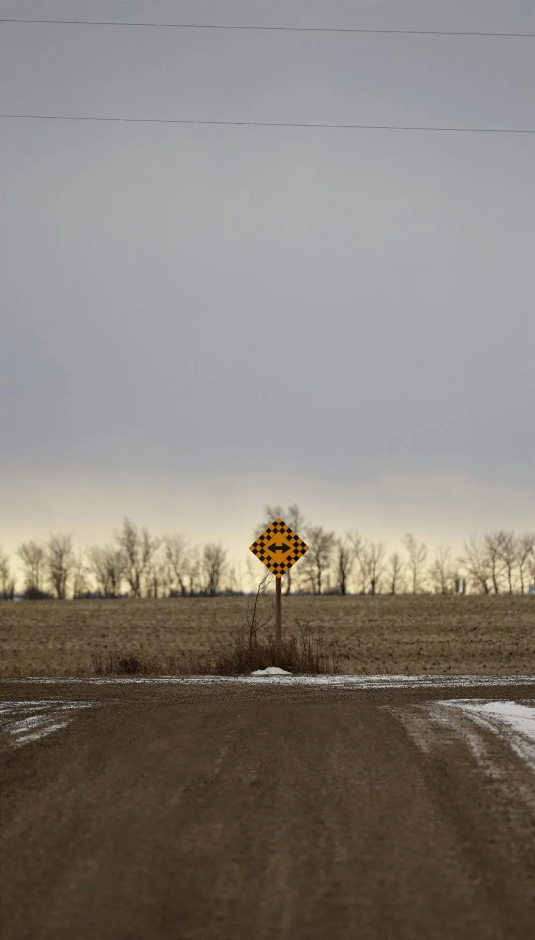 A yellow directional sign marking a T-intersection where a rural road ends and traffic must turn left or right